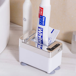 Touchless automatic toothpaste dispenser with a hand reaching towards the sensor to dispense toothpaste onto a toothbrush